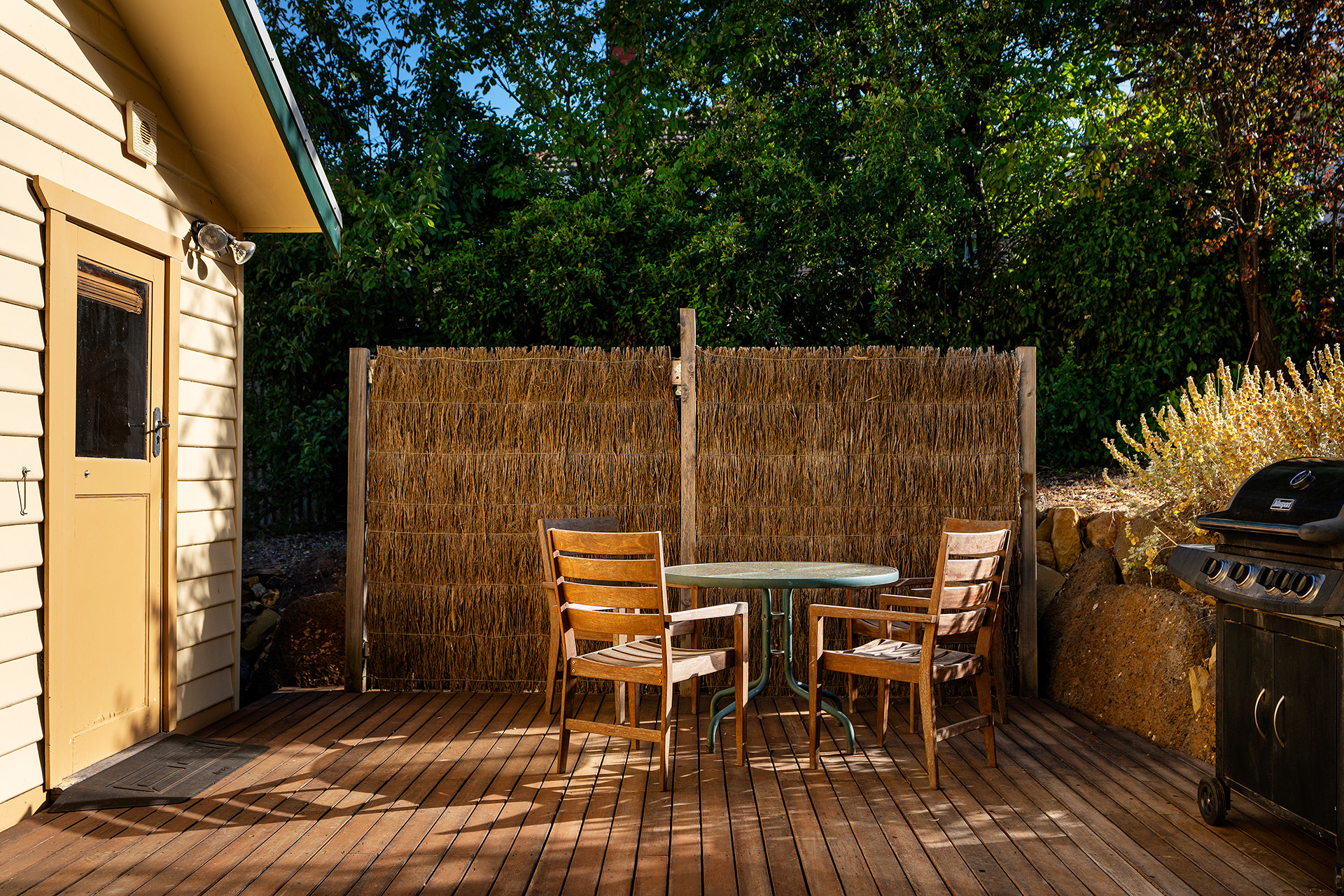 Private timber deck with dining setting at a managed short-term rental
